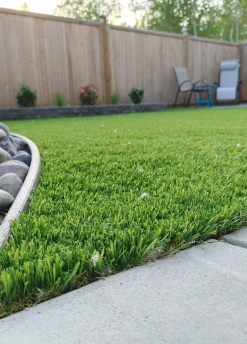 Artificial turf next to a rock garden with a separator in a backyard