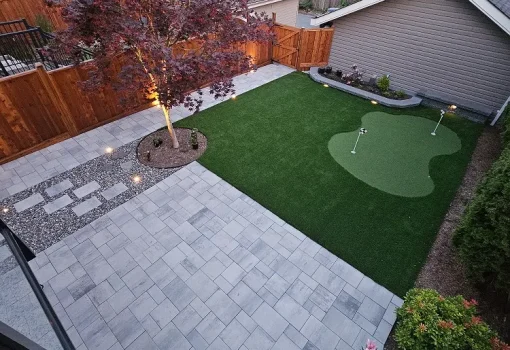 back yard putting green and artificial turf that also shows a paverstone patio sitting area